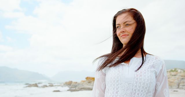 Woman Smiling at Beachside with Wind Swept Hair on Cloudy Day - Download Free Stock Images Pikwizard.com