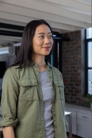 Confident Asian Woman in Modern Loft Office Wearing Olive Green Shirt