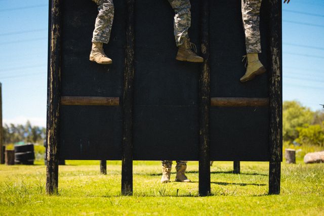 Low section of multiracial mid adult male and female soldiers on wooden obstacle during training. unaltered, military recruit, military training, cross training, exercising and obstacle course.