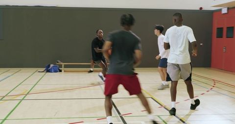 Diverse friends playing indoor basketball practicing passing, driving and defense
