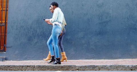 American African Twins Walking in Urban Area Using Mobile Phone
