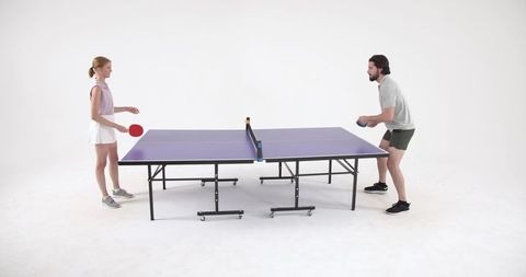 Man and Woman Competing in Table Tennis Match in Modern Studio