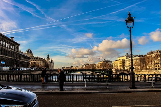 Depicting a vibrant morning in Paris, this scene shows historical buildings lining the river with a bridge spanning across, under a sky adorned with contrail patterns. Ideal for travel blogs, city guides, and cultural articles.