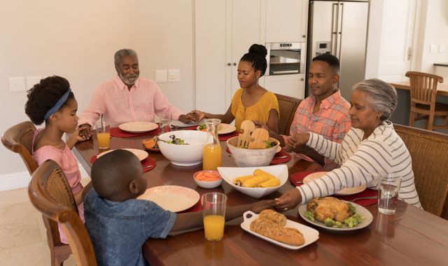 High angle view of a  African American multi-generation family holding their hands and praying together before having meal on dining table at home