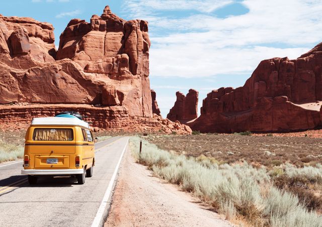Vintage yellow van traveling along a deserted road through a canyon with majestic red rock formations. Ideal for illustrating themes of travel, adventure, freedom, and exploration. Captures the essence of a road trip, perfect for posters, travel blogs, brochures, and adventure-themed marketing materials.