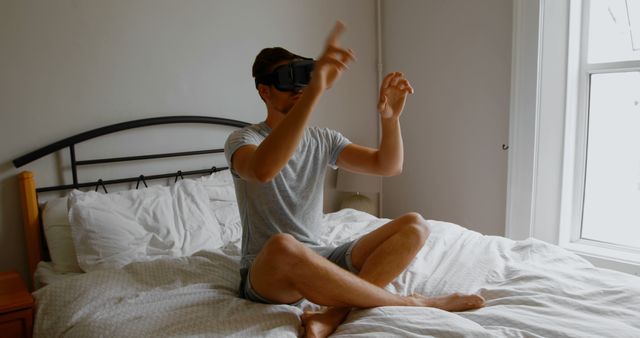 Man Using Virtual Reality Headset on Bed in Bright Bedroom - Download Free Stock Images Pikwizard.com