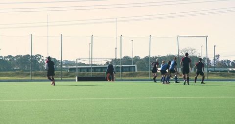 Teenage Hockey Players Competing on Turf Field Near Goal
