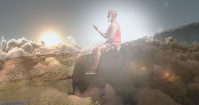 Man Sitting on Edge of Cliff Above Clouds Using Smartphone - Download Free Stock Images Pikwizard.com