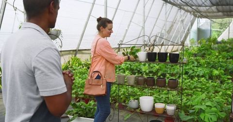 Customer and vendor exploring ceramic pots greenhouse environment