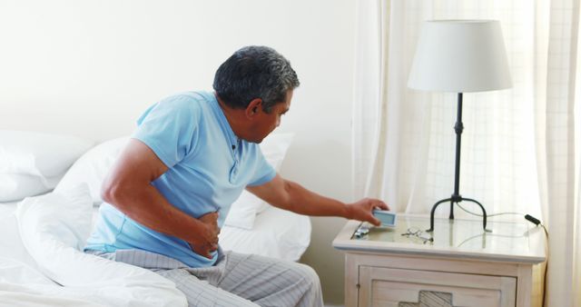 Senior Man Waking Up with Stomach Pain and Turning Off Alarm Clock - Download Free Stock Images Pikwizard.com