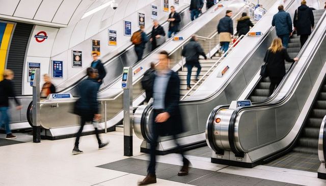 Commuters navigating escalators in busy london underground station during rush hour