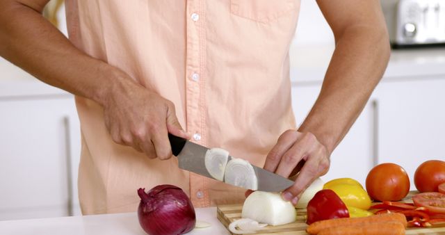 Midsection of a man chopping vegetables on a cutting board. Ideal for illustrating food preparation, healthy eating habits, culinary skills, and home cooking. Also useful for cooking blog visuals, recipe books, and advertisement for kitchen appliances or cookery courses.