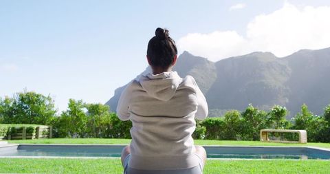 Woman Meditating by Pool with Mountain View