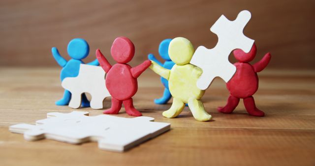 Colorful figurines work together to connect puzzle pieces, symbolizing teamwork and collaboration. Their joint effort represents the importance of cooperation in achieving common goals.