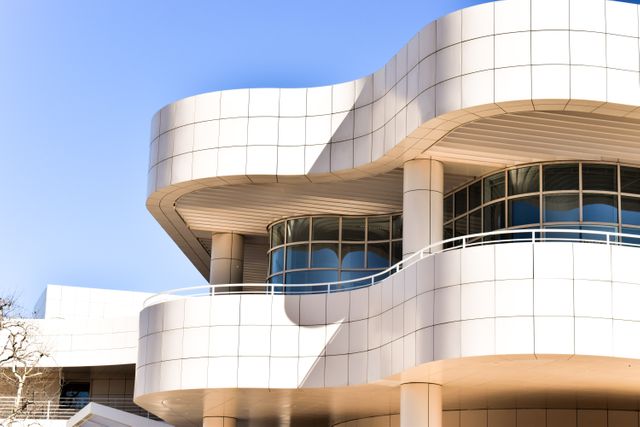 Modern architectural design is highlighted with its curved facades and large, glass windows against a clear blue sky. This image can be used for promoting architectural firms, urban design concepts, construction companies, innovative building materials, and interior design inspirations.
