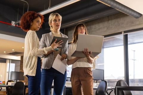 Diverse female team analyzing documents in modern office