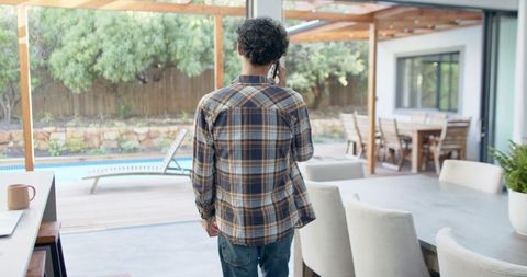 Man Calling on Patio Overlooking Pool with Laptop and Mug Nearby