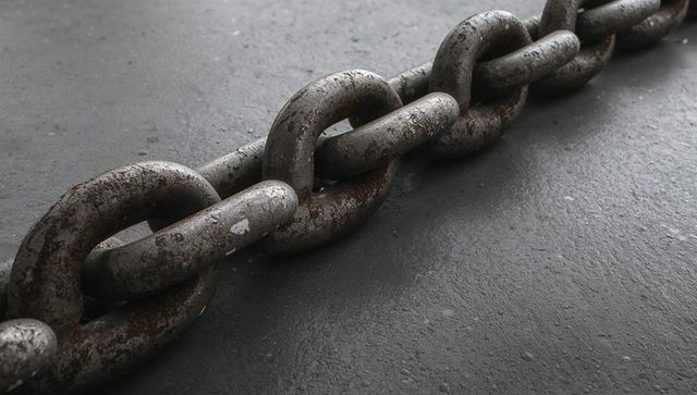 Rusted heavy steel chain resting diagonally on concrete floor closeup industrial texture