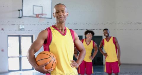 Confident basketball player holding ball with teammates