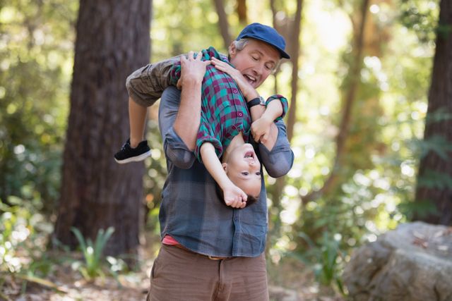 Playful father carrying little son while hiking in forest