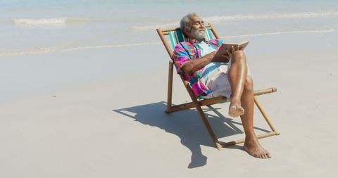Senior Man Relaxing on Beach in Colorful Shirt with Book - Download Free Stock Images Pikwizard.com