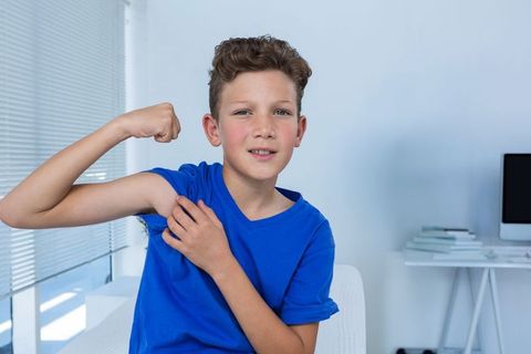 Young boy flexing arm muscles in home office environment