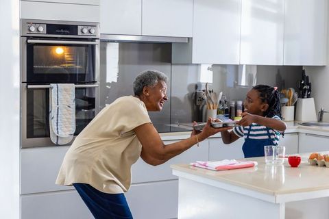 Grandmother and granddaughter baking together sharing joyful moment in modern kitchen