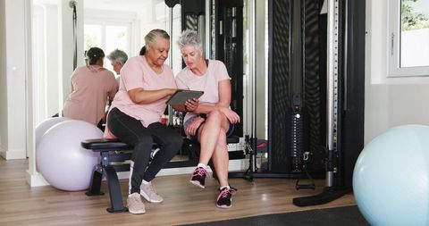 Senior Women Using Tablet at Home Gym Promoting Fitness