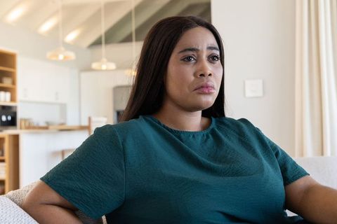 Contemplative african american woman checking thermostat in modern living room