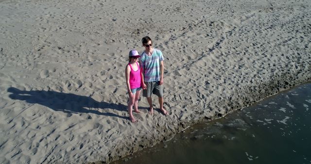 Couple Standing on Beach Holding Hands with Shadows at Sunset - Download Free Stock Images Pikwizard.com