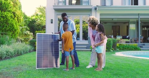 Diverse family examining solar panel in backyard of modern two-story home near pool