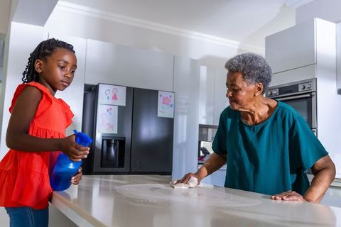 African grandmother and granddaughter cleaning kitchen counter, multigenerational bonding