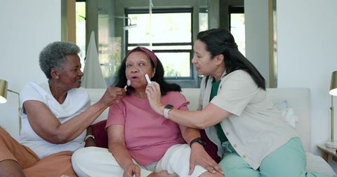 Multigenerational african american women sharing skincare routine with facial rollers