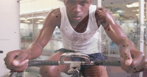 Intense indoor cycling workout man gripping spin bike handlebars pedaling in gym studio
