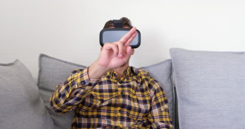 Man Sitting on Sofa Using Virtual Reality Headset Indoors