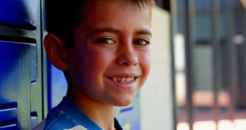 Smiling schoolboy standing near lockers with bright smile