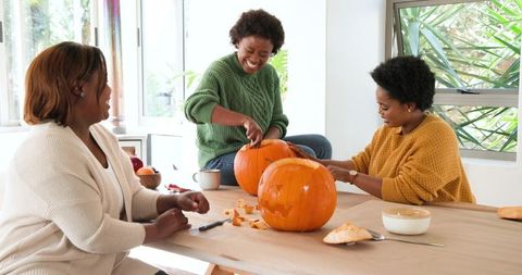 Friends carving pumpkins at home in autumn for festive diy activity