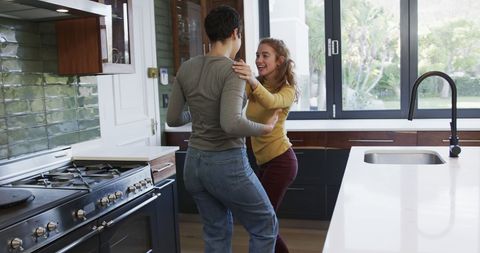 Happy Lesbian Couple Embracing in Modern Sunlit Kitchen