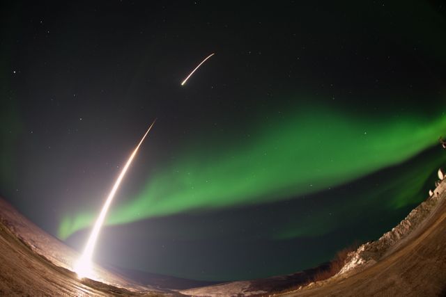 A NASA-funded sounding rocket launches into an aurora over Venetie, Alaska, on March 3, 2014. The GREECE mission investigates how certain structures form within the aurora. This stunning nighttime scene, featuring visible streaks from the rocket against a vibrant green aurora, exemplifies scientific discovery and the allure of space exploration. Ideal for use in educational materials, science presentations, and articles on space missions or atmospheric phenomena.