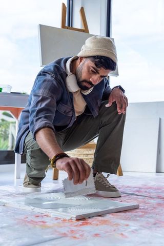 Artist creating textured panel with notched trowel in sunlit studio