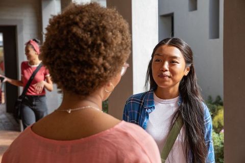 Chinese student chatting with peer on campus walkway, casual college conversation