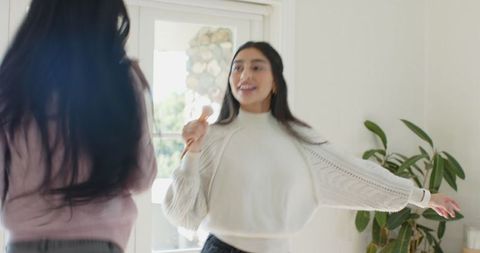 Diverse Female Friends Singing in Living Room with Hairbrush Microphones