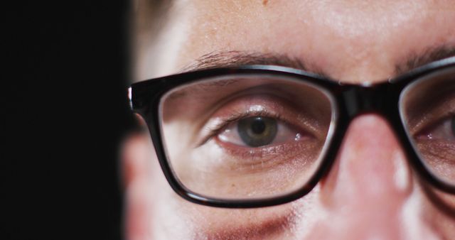 Shows close-up view of man's face focused on glasses and eyes. Useful for concepts such as corrective lenses, eye care, mental focus, contemplation, attention to detail, optical clarity or personal thinking space.