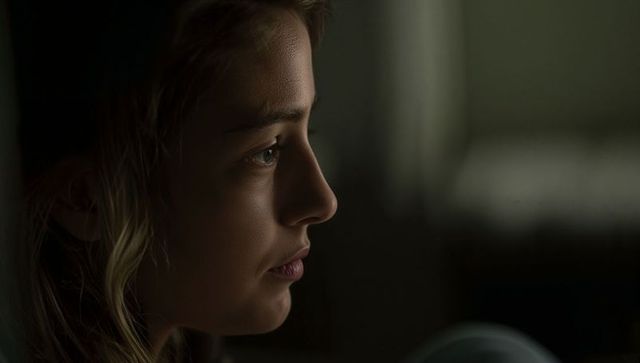 Adolescent girl gazing toward window in dim interior, contemplative close-up portrait