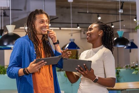 African american coworkers collaborating with tablets and smartwatches in vibrant coworking