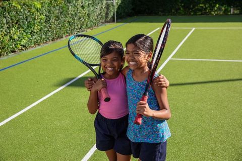 Smiling Girls Holding Tennis Rackets on Outdoor Court