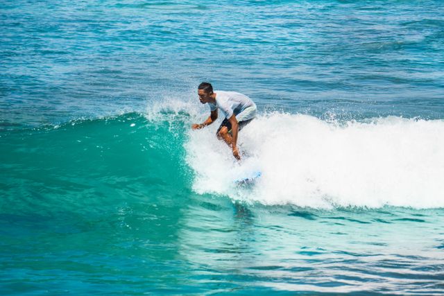 Young man surfing on an ocean wave on a bright, sunny day, perfect for beach, adventure, and travel content. Highlights active lifestyle, water sports, and enjoying vacation.