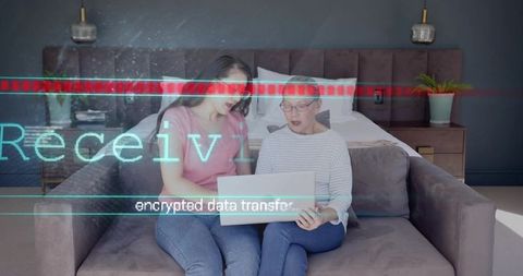 Mother and daughter sitting on sofa using laptop with encrypted data transfer overlay