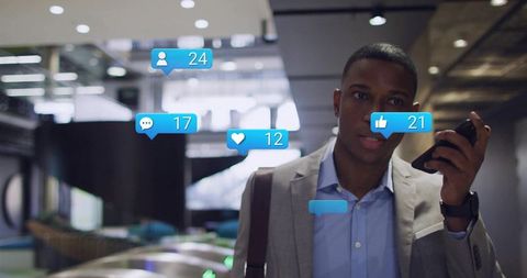 Talking businessman holding smartphone with social media notifications in modern lobby