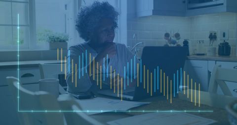 Senior woman analyzing financial data on laptop in kitchen